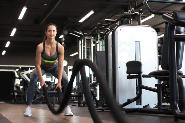 Fit woman using battle ropes during strength training at the gym - Foto, immagini