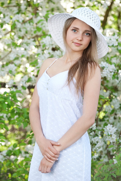Girl in a hat among  blossoming trees - Foto, Imagen