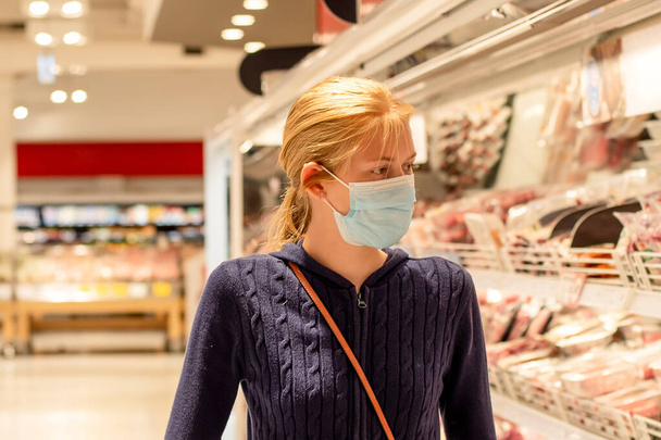 Het dragen van gezichtsmaskers in winkelcentra zijn verplicht in Greater Sydney NSW. Een meisje met een wegwerpmasker in de supermarkt. COVID-19 beperkingen. - Foto, afbeelding