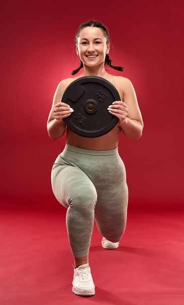 Confident plus size young woman in fitness attire exercising at studio  - Fotografie, Obrázek