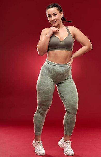 Confident plus size young woman in fitness attire exercising at studio  - Foto, imagen