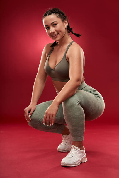 Confident plus size young woman in fitness attire exercising at studio  - 写真・画像