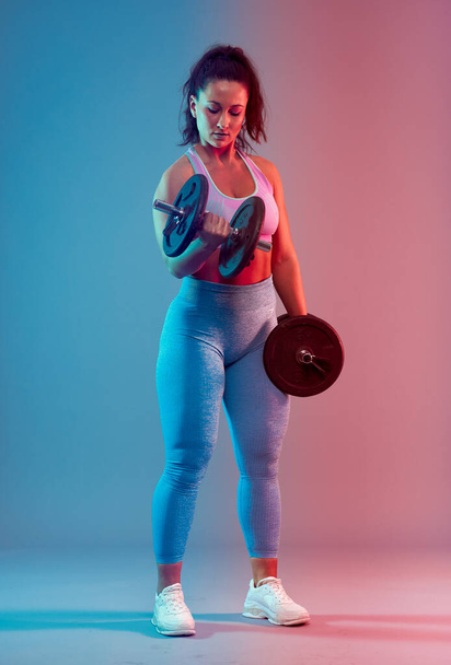 Confident plus size young woman in fitness attire exercising at studio  - Foto, afbeelding