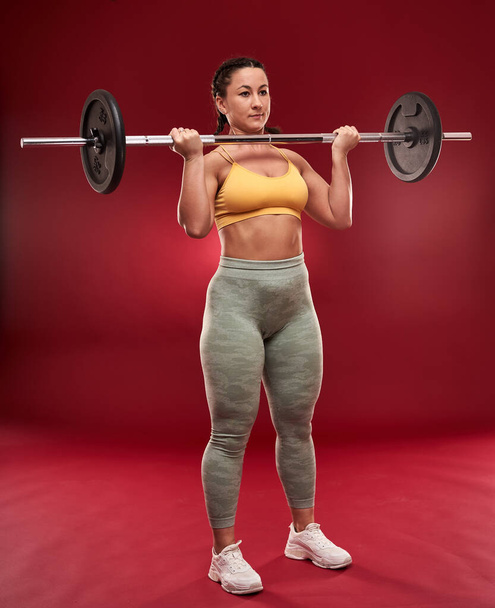 Confident plus size young woman in fitness attire exercising at studio  - Photo, image
