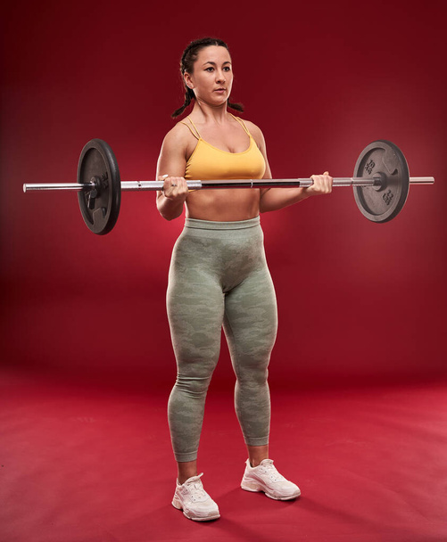 Confident plus size young woman in fitness attire exercising at studio  - Photo, image