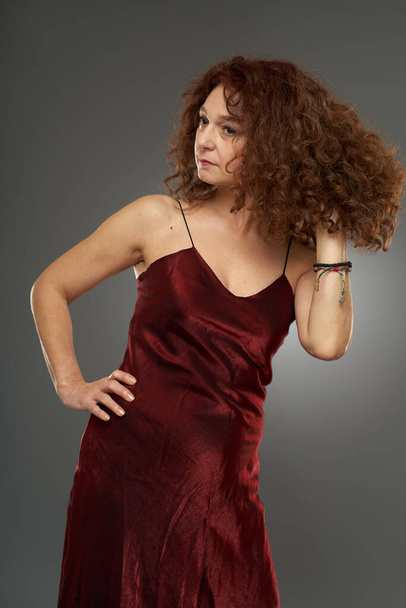 Beauty at 50. Studio portrait of a mature curly haired woman in long dress - Foto, Imagem