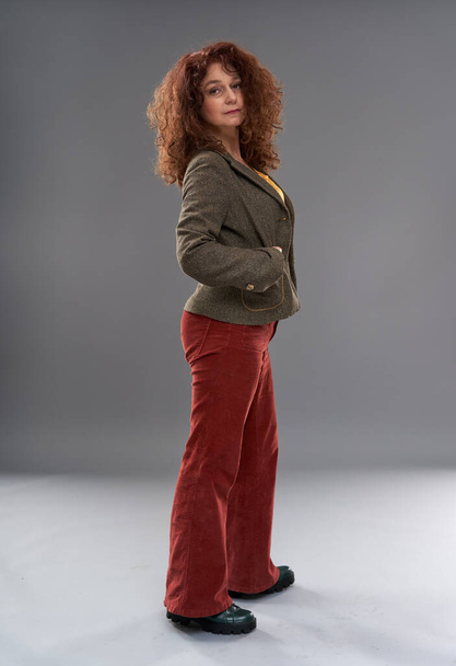 Curly redhead mature woman portrait, studio shot on gray background - Photo, Image