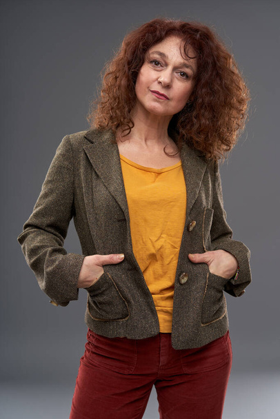 Curly redhead mature woman portrait, studio shot on gray background - Фото, зображення