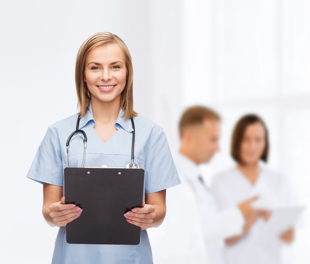 Smiling female doctor or nurse with clipboard - Zdjęcie, obraz