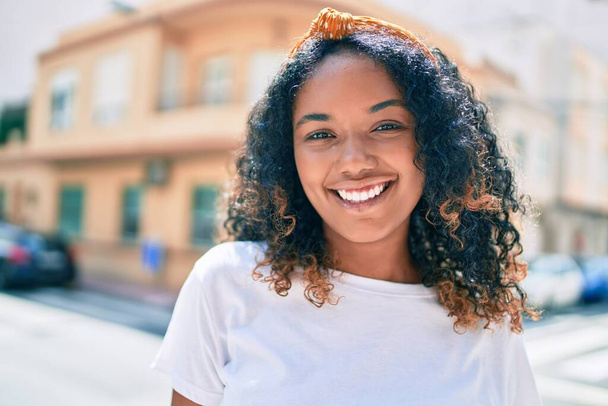 Young african american woman with curly hair smiling happy outdoors - Photo, image