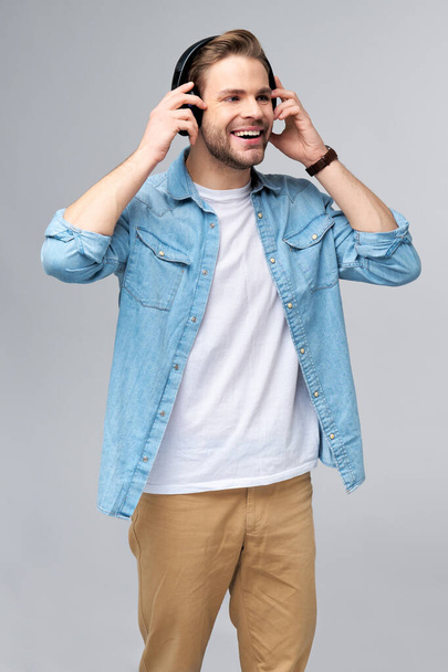 Close up portrait of cheerful young man enjoying listening to music wearing casual jeans outfit - Foto, afbeelding