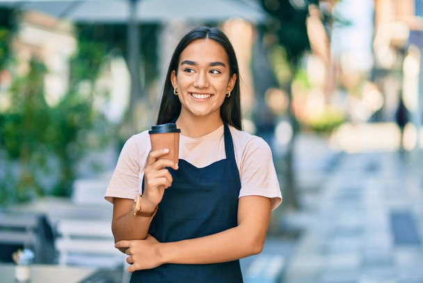 Młoda latynoska barista dziewczyna uśmiechnięta szczęśliwy gospodarstwa zabrać kawę w kawiarni - Zdjęcie, obraz
