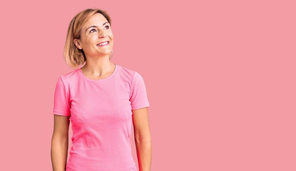 Young blonde woman wearing sportswear looking away to side with smile on face, natural expression. laughing confident.  - Foto, imagen