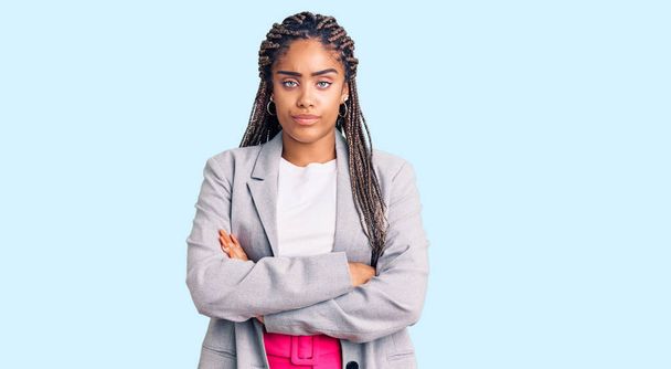 Młoda Afroamerykanka z warkoczami w ubraniu biznesowym, sceptyczna i nerwowa, nie aprobująca wyrazu twarzy z skrzyżowanymi ramionami. osoba negatywna.  - Zdjęcie, obraz