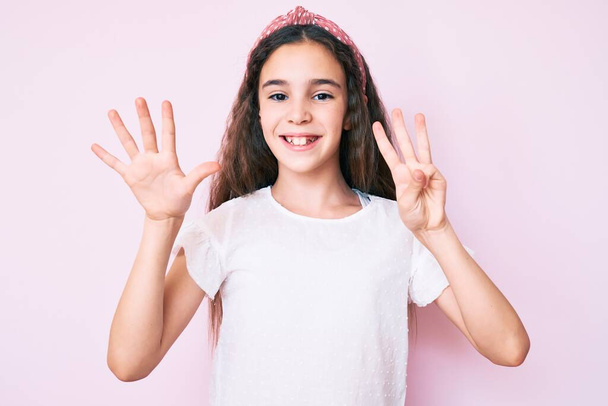 Aranyos spanyol gyerek lány visel alkalmi ruhák és diadém mutatja, és rámutatva ujjak száma 8 miközben mosolygós magabiztos és boldog.  - Fotó, kép