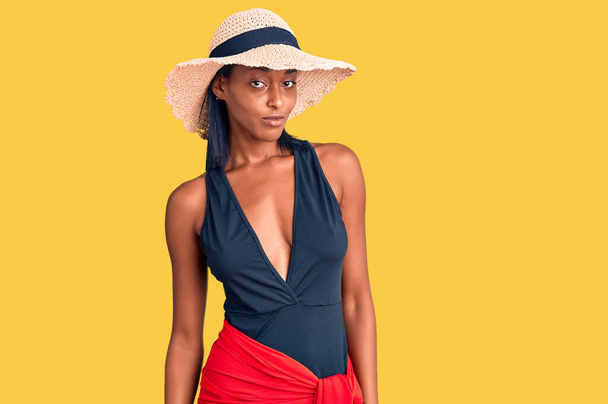 Young african american woman wearing swimsuit and summer hat looking sleepy and tired, exhausted for fatigue and hangover, lazy eyes in the morning.  - Фото, зображення