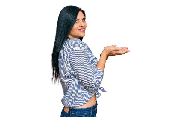 Giovane donna caucasica indossa abiti casual indicando da parte con le mani aperte palme che mostrano spazio copia, presentando pubblicità sorridente eccitato felice  - Foto, immagini