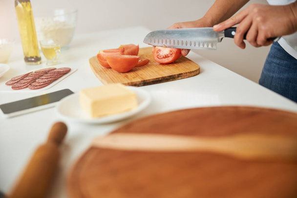 Κόβοντας ντομάτες με το πιο κοφτερό μαχαίρι στην κουζίνα - Φωτογραφία, εικόνα