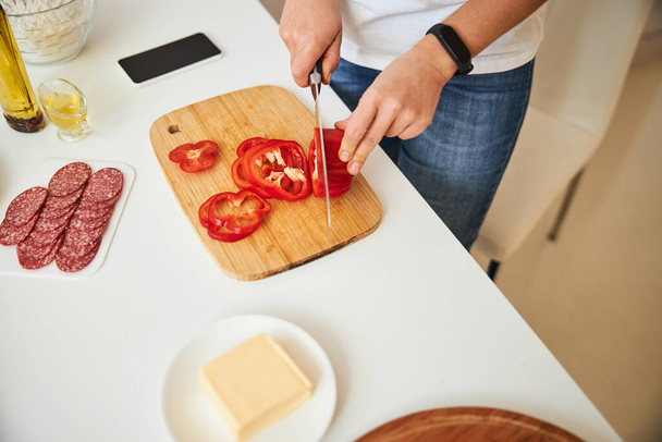 Person making smooth slices of pepper for the meal - Foto, afbeelding