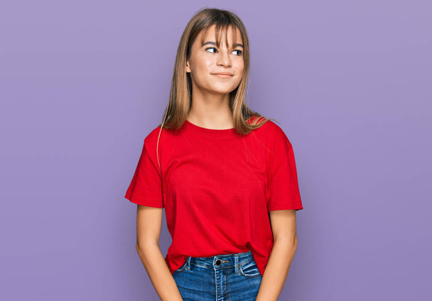 Teenager caucasian girl wearing casual red t shirt smiling looking to the side and staring away thinking.  - 写真・画像