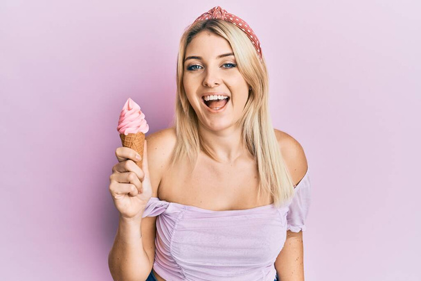 Jonge blanke vrouw die een ijsje vasthoudt, lachend en hard lachend, omdat ze een gekke grap uithaalt..  - Foto, afbeelding