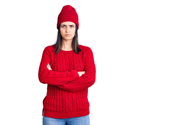 Young beautiful girl wearing sweater and wool cap skeptic and nervous, disapproving expression on face with crossed arms. negative person.  - Photo, image