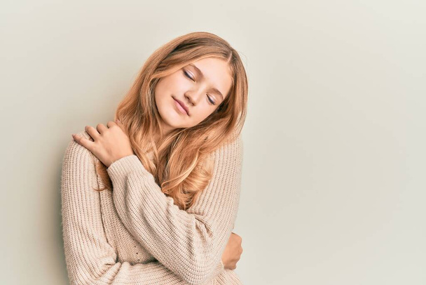 Beautiful young caucasian girl wearing casual clothes hugging oneself happy and positive, smiling confident. self love and self care  - Foto, afbeelding