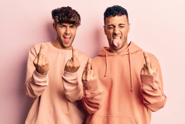 Young gay couple wearing casual clothes showing middle finger doing fuck you bad expression, provocation and rude attitude. screaming excited  - Φωτογραφία, εικόνα