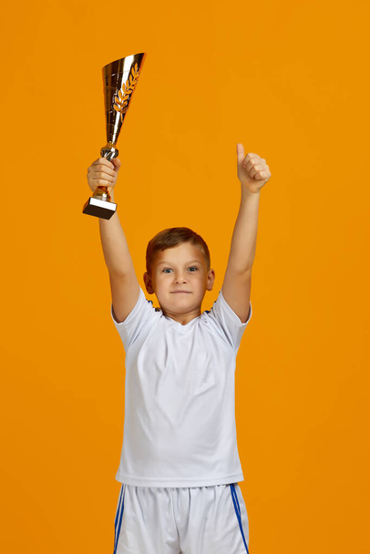 Football player holding a golden cup - Foto, Imagen