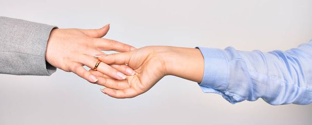 Ruka kavkazské mladé ženy uvedení zlatý svatební prsten s jinou osobou přes izolované bílé pozadí - Fotografie, Obrázek