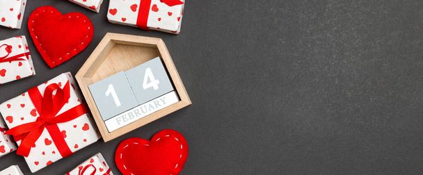 Holiday composition of gift boxes, wooden calendar and red textile hearts on colorful background with empty space for your design. The fourteenth of February. Top view of Valentine's Day concept. - Zdjęcie, obraz