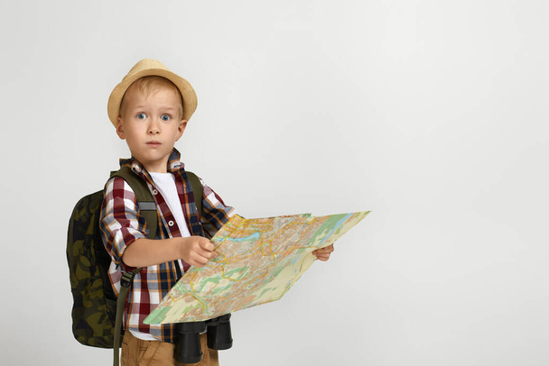 Little boy tourist with backpack holding binoculars and map. - Foto, Imagem