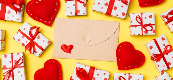 Vista superior del colorido fondo de San Valentín hecho de sobre artesanal, cajas de regalo y corazones textiles rojos. Concepto de San Valentín. - Foto, imagen