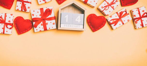 Top view of gift boxes, wooden calendar and red textile hearts on colorful background. The fourteenth of february. St Valentine's day concept with copy space. - Photo, Image