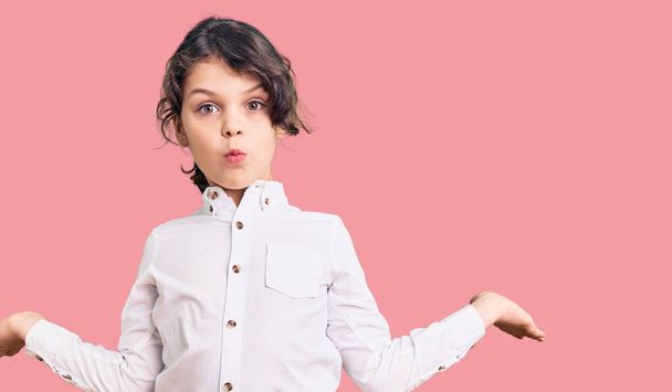 Aranyos spanyol gyerek hétköznapi ruhát visel tudatlan és zavaros kifejezés a karok és a kezek emelt. kétség.  - Fotó, kép