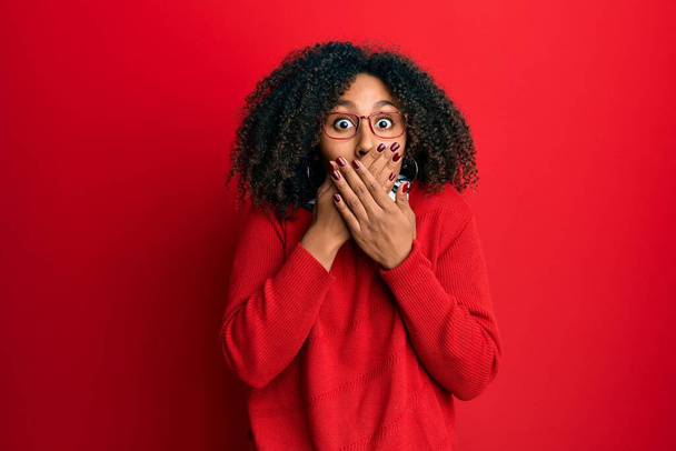 Beautiful african american woman with afro hair wearing sweater and glasses shocked covering mouth with hands for mistake. secret concept.  - Fotoğraf, Görsel