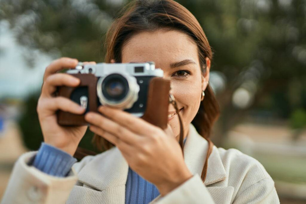 Junge hispanische Touristin lächelt glücklich mit Oldtimer-Kamera im Park. - Foto, Bild
