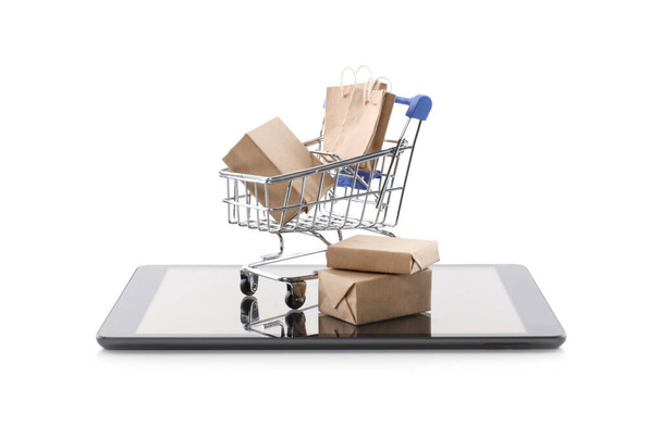 Small cart with bags and boxes on modern tablet against white background. Internet shopping - Foto, imagen