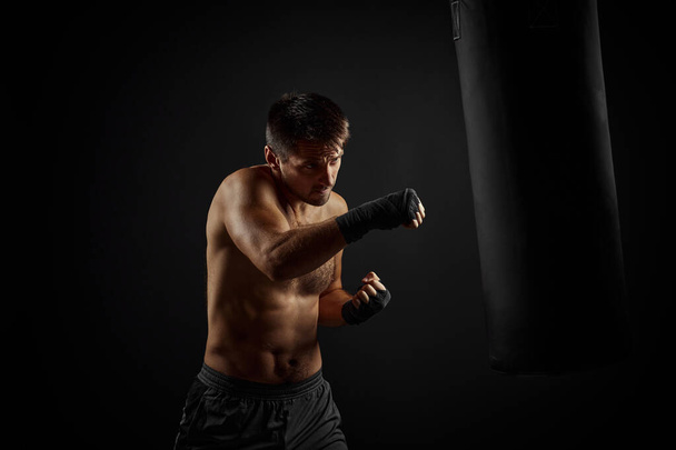 Male boxer punching in boxing bag - 写真・画像