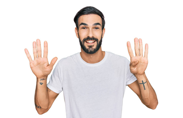 Nuori latinomies yllään rento valkoinen t paita osoittaa ylös sormilla numero yhdeksän hymyillen itsevarma ja onnellinen.  - Valokuva, kuva
