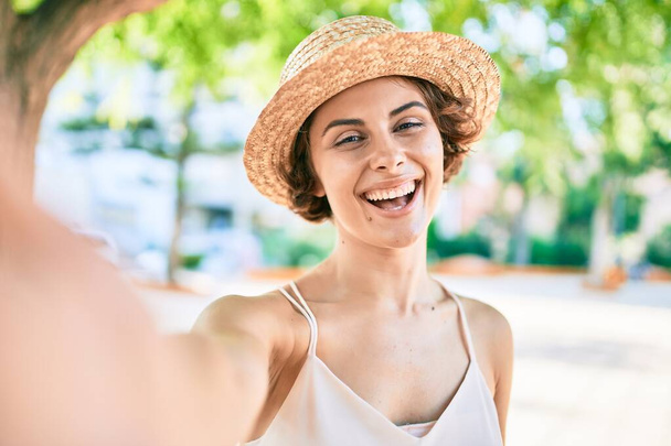Young hispanic woman on vacation smiling happy making selfie by the camera at the park - Фото, изображение