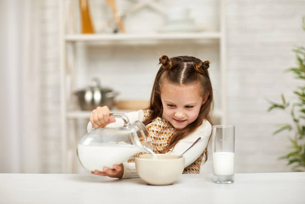 little girl eating breakfast: cereal with the milk. - Zdjęcie, obraz