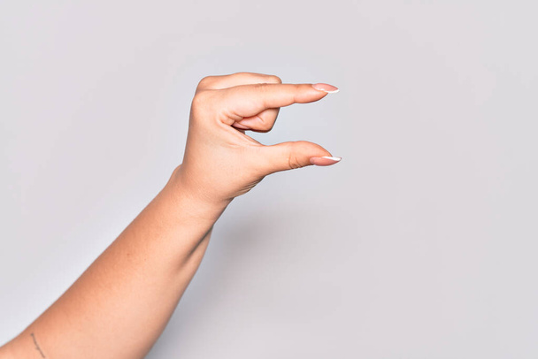 Mano de mujer joven caucásica recogiendo y tomando cosa invisible, sosteniendo el objeto con los dedos mostrando espacio - Foto, Imagen