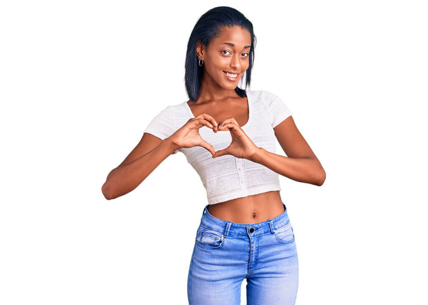 Młoda Afroamerykanka ubrana w luźne ubrania, uśmiechnięta miłością, z symbolami serca i kształtem dłoni. romantyczna koncepcja.  - Zdjęcie, obraz