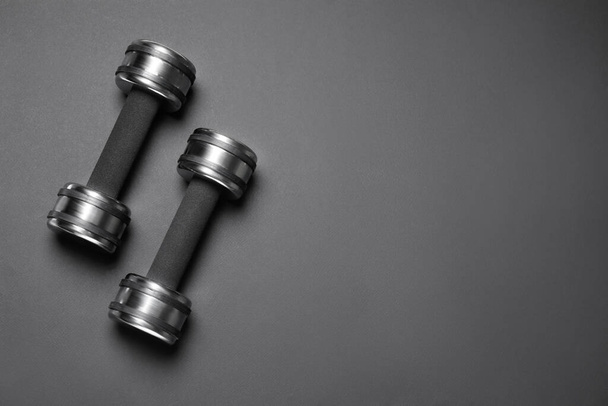 Metal dumbbells on black background, flat lay. Space for text - Foto, immagini