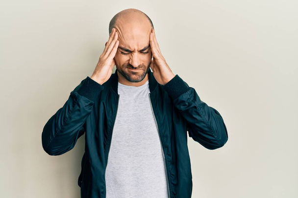 Young hispanic man wearing casual sporty jacket with hand on head, headache because stress. suffering migraine.  - Photo, image