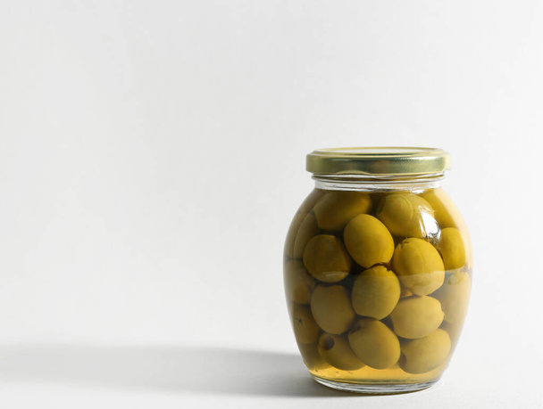 Скляна банка з маринованими оливками на білому тлі. Простір для тексту
 - Фото, зображення