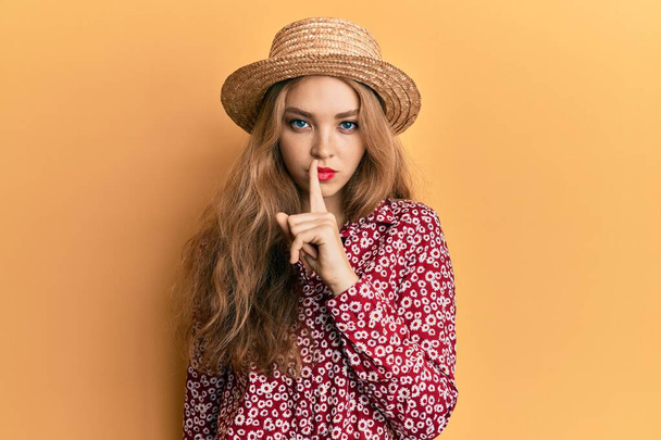 Belle femme caucasienne blonde portant un chapeau d'été demandant à être calme avec le doigt sur les lèvres. silence et concept secret.  - Photo, image