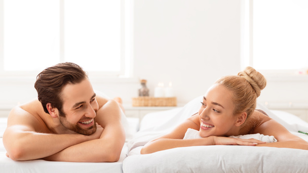 Entspannte Ehepartner im Spa liegen auf Betten und lächeln einander an - Foto, Bild