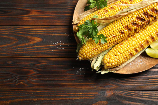 Delicious grilled corn cobs on wooden table, top view. Space for text - Fotoğraf, Görsel